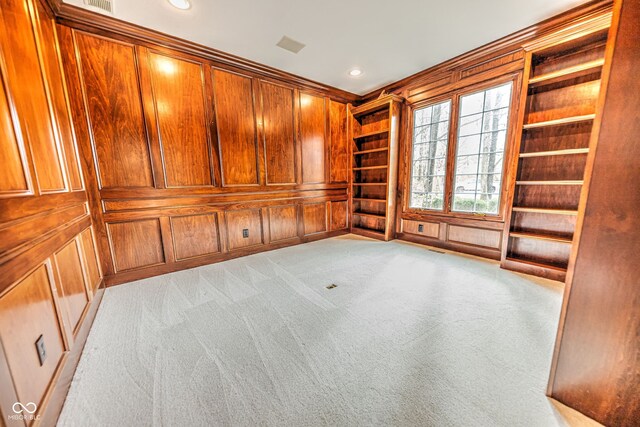 interior space featuring light colored carpet, wooden walls, and built in features