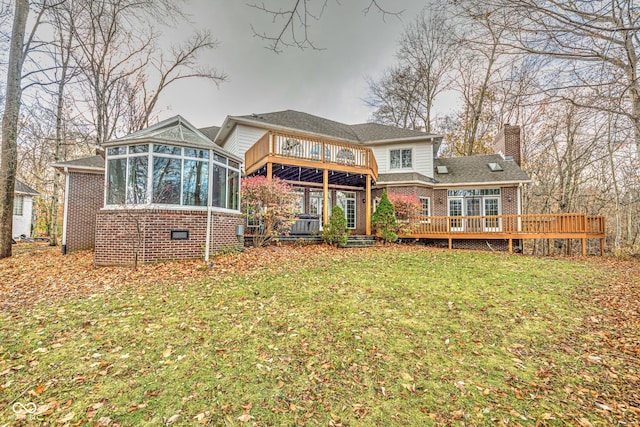 back of house with a wooden deck, a lawn, and a sunroom