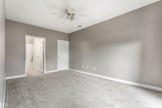 unfurnished bedroom featuring light colored carpet, ceiling fan, and ensuite bath