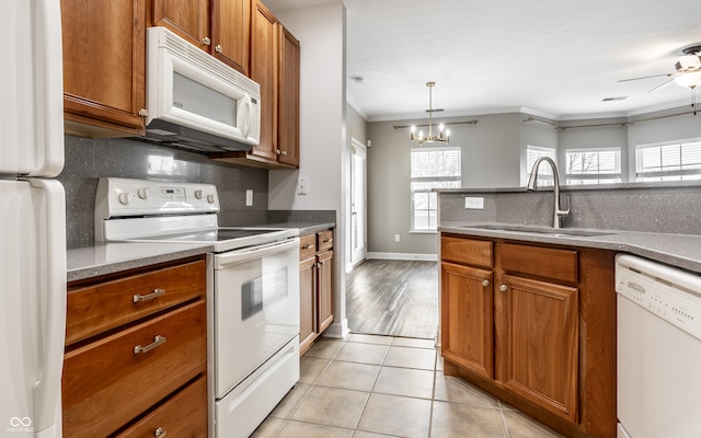 kitchen featuring sink, light tile patterned floors, hanging light fixtures, white appliances, and crown molding