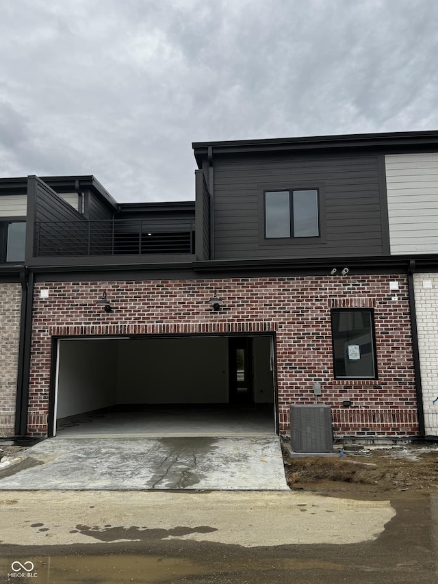 view of front of home with a garage and central AC