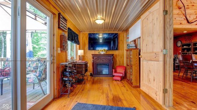 sitting room with wooden walls, wooden ceiling, and light wood-type flooring