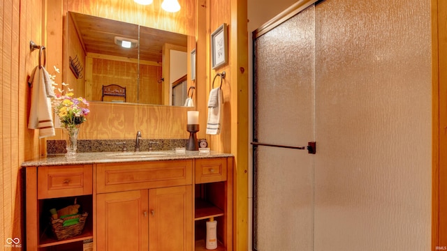 bathroom featuring a shower with door, vanity, and wooden walls