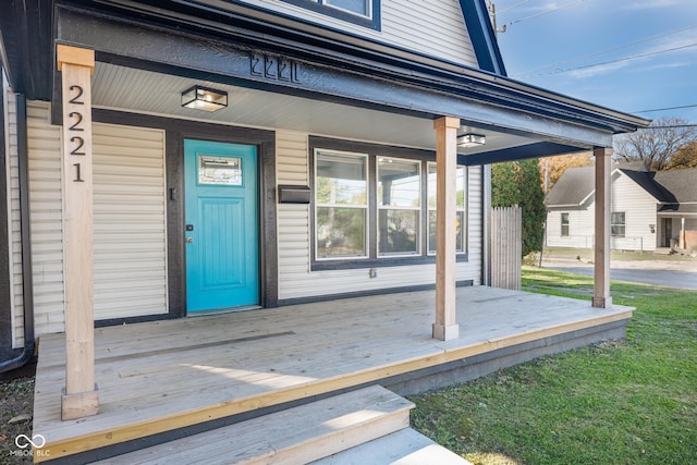 doorway to property featuring a porch and a lawn