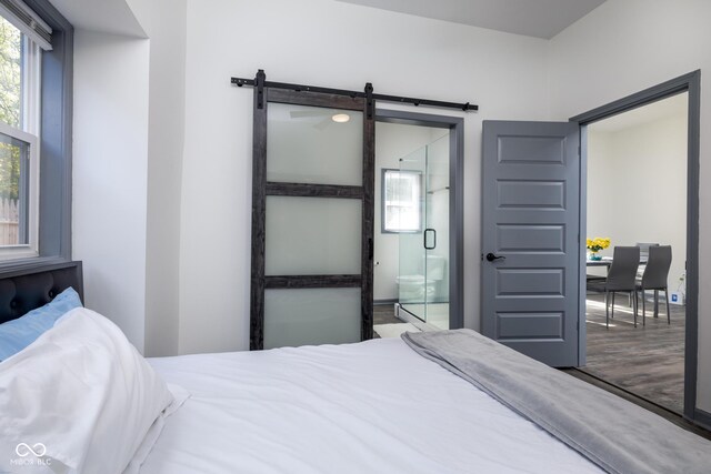 2221 E Michigan St, Indianapolis, IN 46201 - bedroom with a barn door, wood finished floors, ensuite bath, and multiple windows