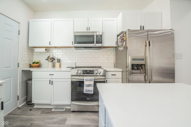 kitchen featuring stainless steel appliances, decorative backsplash, light hardwood / wood-style flooring, and white cabinets