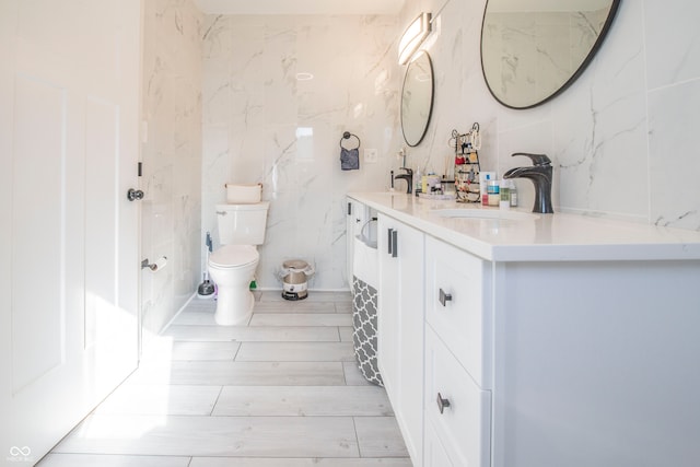 bathroom featuring vanity, toilet, and tile walls