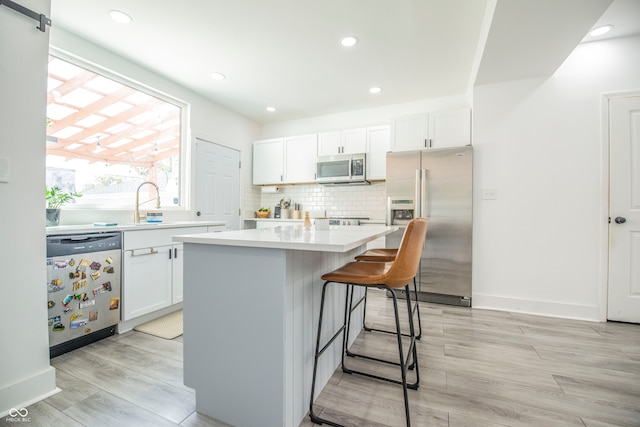 kitchen with a kitchen island, white cabinetry, light hardwood / wood-style flooring, and stainless steel appliances