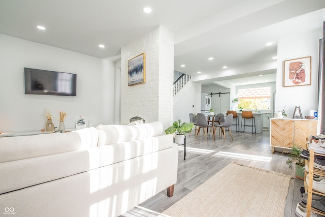 living room featuring a fireplace, light hardwood / wood-style flooring, and a barn door