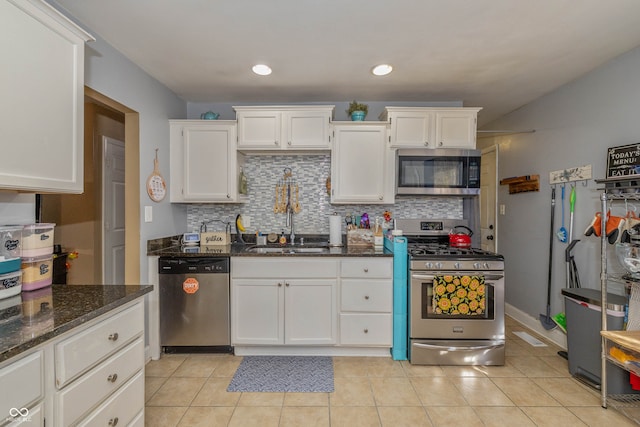 kitchen featuring dark stone countertops, sink, white cabinets, light tile patterned floors, and appliances with stainless steel finishes