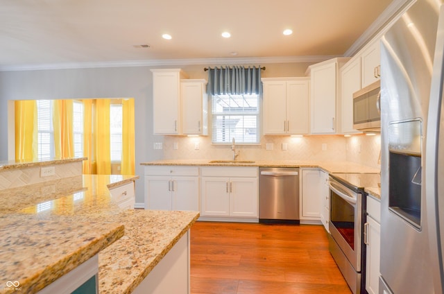 kitchen featuring sink, stainless steel appliances, light hardwood / wood-style flooring, crown molding, and white cabinets