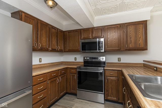 8168 Shorewalk Dr Unit A, Indianapolis, IN 46236 - kitchen featuring crown molding, light wood-type flooring, a sink, and stainless steel appliances