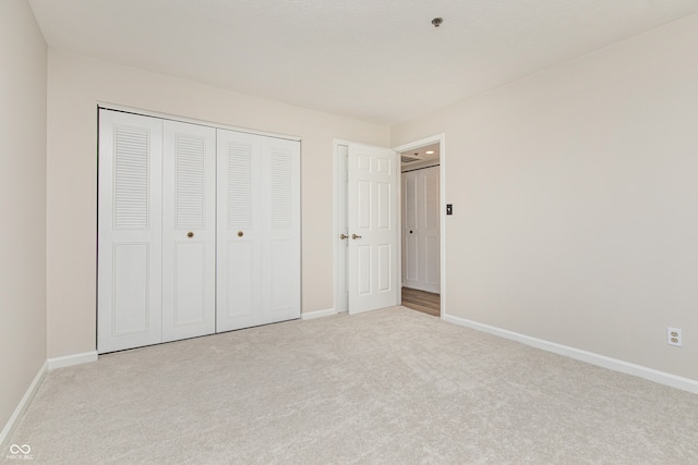 unfurnished bedroom featuring light carpet and a closet