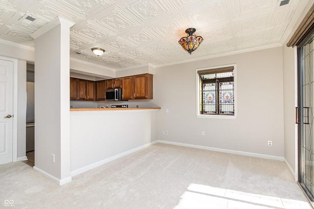 kitchen featuring kitchen peninsula, light colored carpet, and crown molding