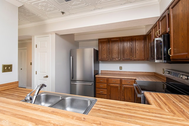 kitchen with stainless steel appliances, sink, wood-type flooring, and butcher block countertops