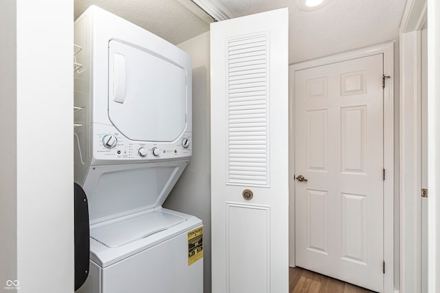 washroom with stacked washer and dryer, a textured ceiling, and hardwood / wood-style flooring