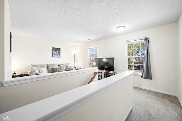 hallway featuring a textured ceiling and light colored carpet