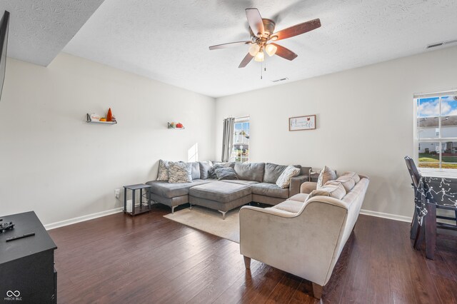 living room with ceiling fan, a textured ceiling, a wealth of natural light, and dark hardwood / wood-style floors