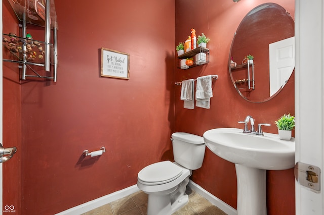 bathroom with toilet, sink, and tile patterned flooring