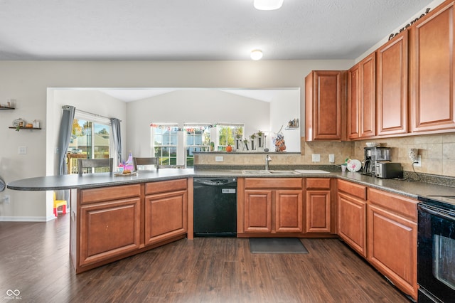 kitchen with lofted ceiling, dark wood-type flooring, kitchen peninsula, sink, and black appliances