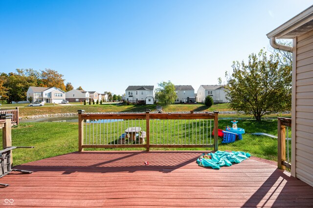 wooden terrace with a water view and a lawn