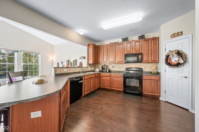 kitchen with black appliances, sink, dark hardwood / wood-style flooring, kitchen peninsula, and vaulted ceiling