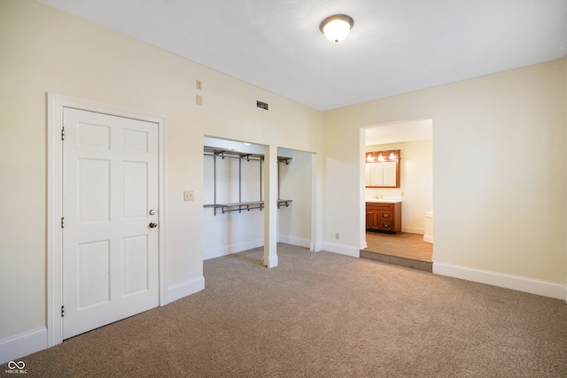 unfurnished bedroom featuring ensuite bathroom and light colored carpet