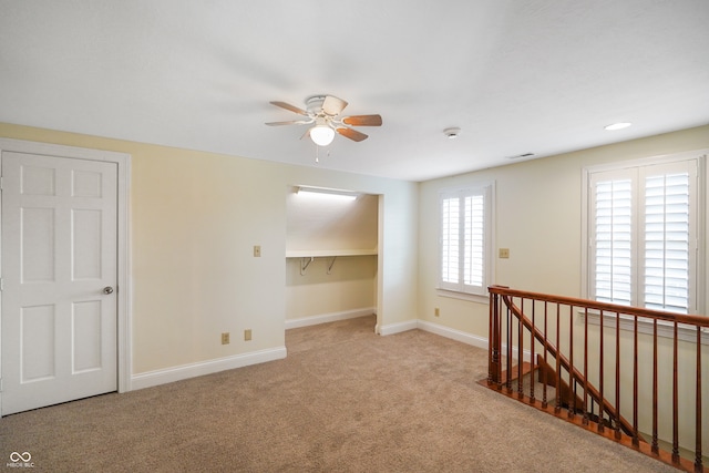 carpeted empty room with ceiling fan and plenty of natural light