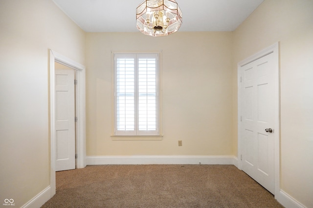 unfurnished room with carpet and a notable chandelier