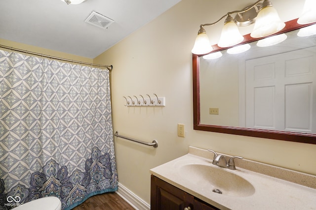 bathroom featuring toilet, vaulted ceiling, hardwood / wood-style flooring, and vanity