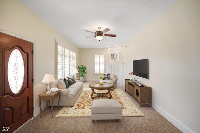 carpeted living room featuring ceiling fan and a textured ceiling