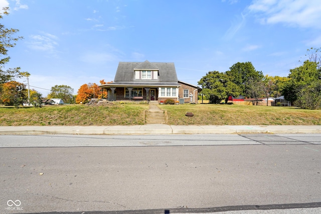 cape cod-style house with covered porch and a front lawn