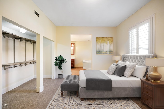 bedroom featuring light colored carpet and connected bathroom