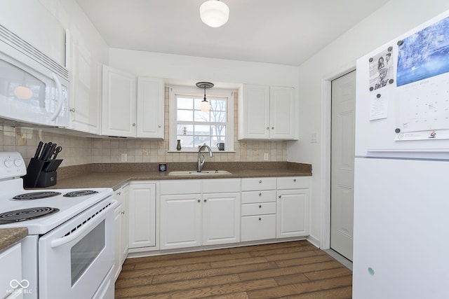 kitchen with a sink, tasteful backsplash, dark countertops, white cabinetry, and white appliances