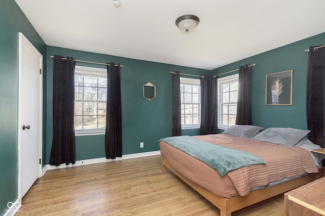 bedroom featuring light wood finished floors, multiple windows, and baseboards