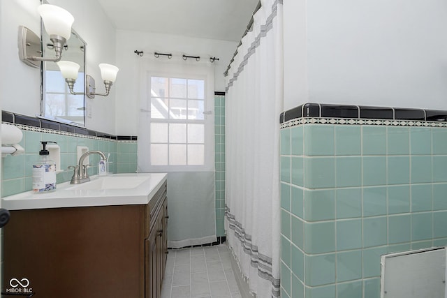 full bathroom with tile patterned floors, tile walls, wainscoting, and vanity