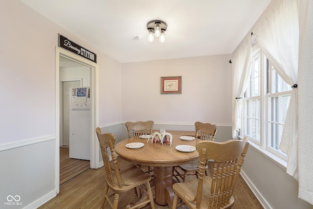 dining space featuring baseboards and light wood finished floors