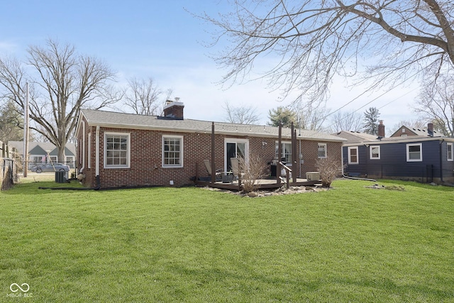 rear view of property featuring a yard, brick siding, a chimney, and fence