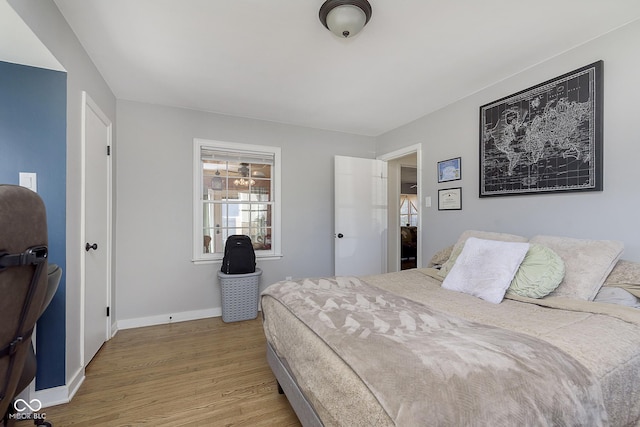 bedroom featuring baseboards, multiple windows, and wood finished floors