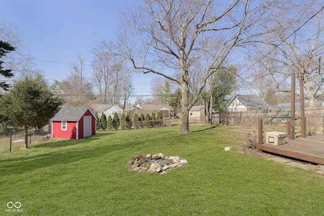 view of yard with a deck, an outdoor structure, a fenced backyard, and a shed