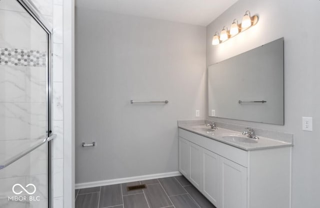 bathroom with a shower with door, a sink, baseboards, and double vanity