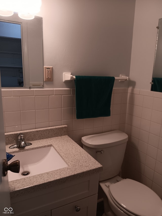 bathroom with vanity, toilet, and tile walls