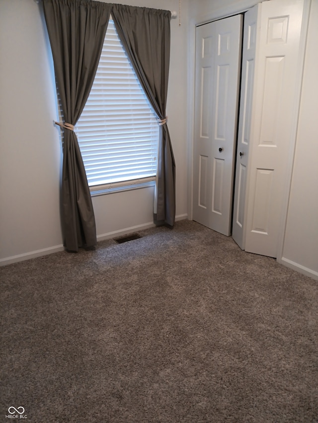 unfurnished bedroom featuring dark colored carpet and a closet