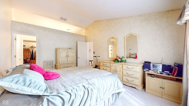 bedroom with light colored carpet, a closet, lofted ceiling, and a walk in closet