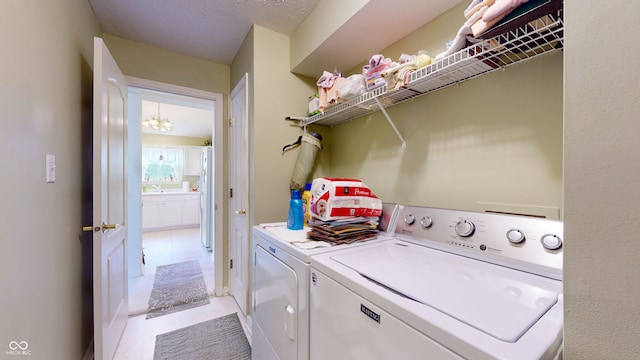 clothes washing area with light tile patterned flooring, independent washer and dryer, and a textured ceiling