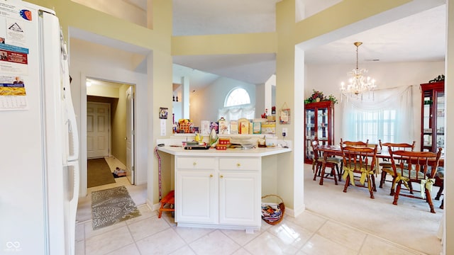 kitchen featuring light carpet, a notable chandelier, pendant lighting, white refrigerator, and white cabinetry