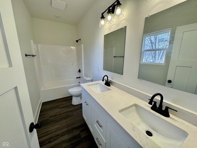 full bathroom featuring a sink, toilet, wood finished floors, and bathtub / shower combination