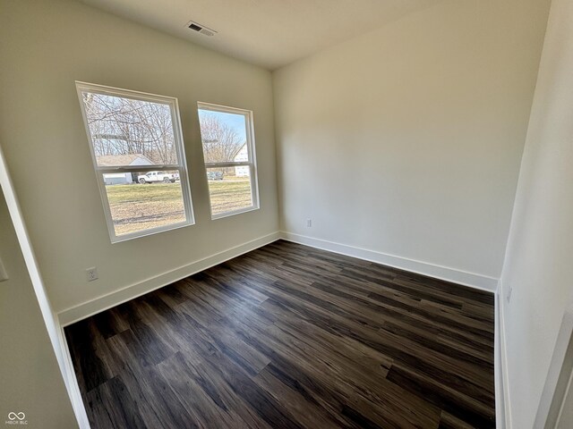 spare room featuring dark wood-style floors, baseboards, and visible vents