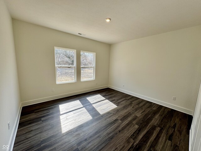 unfurnished room featuring dark wood finished floors, baseboards, and visible vents