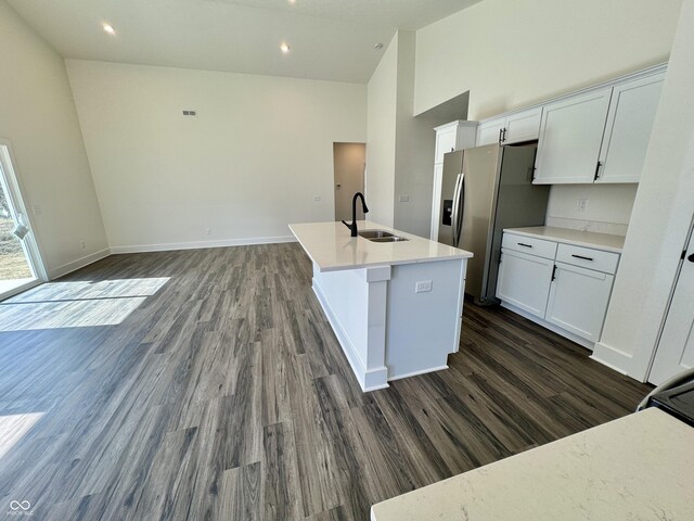 kitchen with dark wood-type flooring, high vaulted ceiling, stainless steel refrigerator with ice dispenser, white cabinetry, and a sink